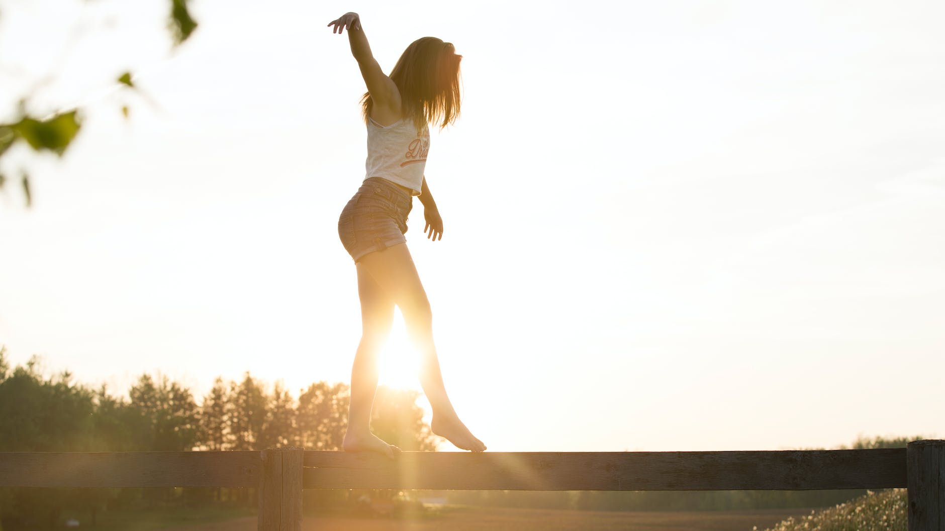 Junge Frau läuft auf einem Zaun und hält das Gleichgewicht  